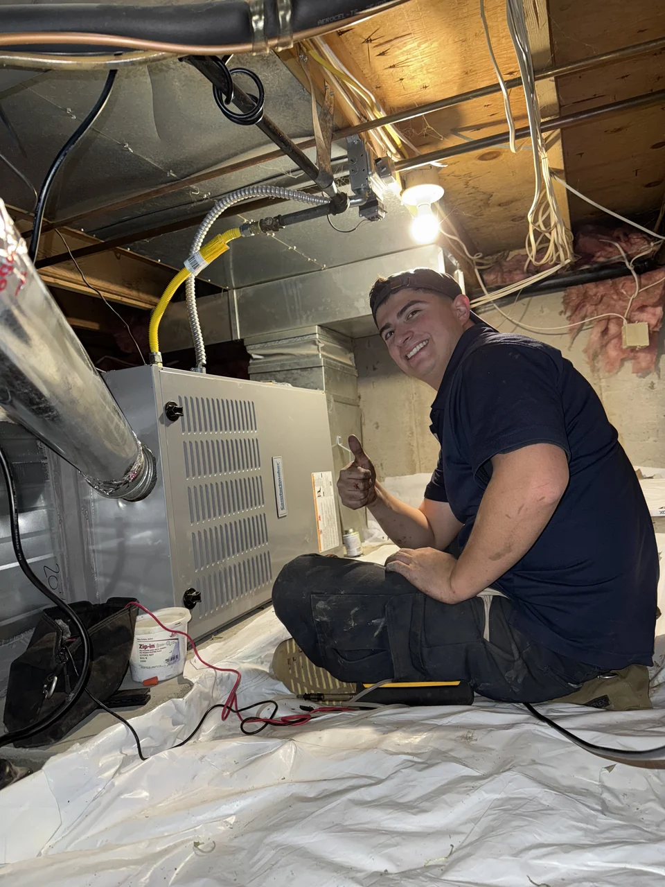 Gerardo beside a furnace during HVAC work